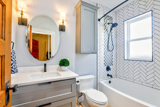 Eine weiße Badezimmer mit zwei Lampen, marmor Waschbecken, Toilette und Badewanne sowie ein Fenster. 